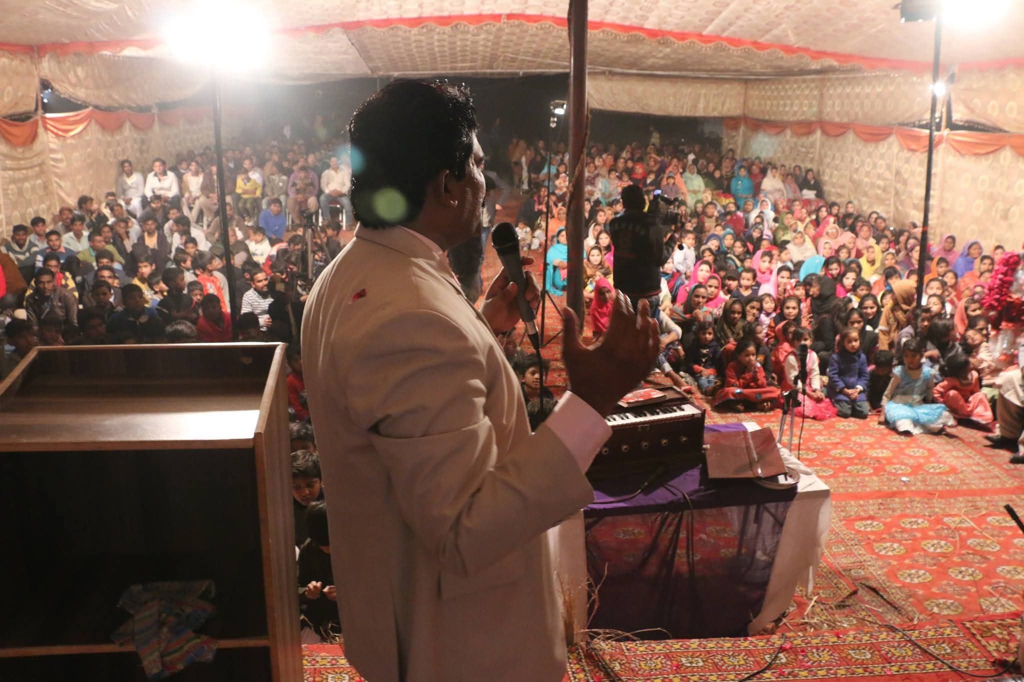 Pastor Arshad Sadiq preaching to a packed tent of men, women and children